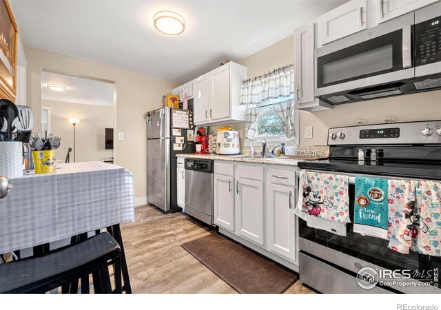 316 14th Ave, Greeley, CO 80631 - kitchen featuring appliances with stainless steel finishes, light countertops, a sink, light wood finished floors, and white cabinetry