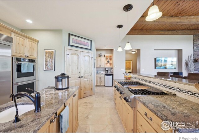 27921 Alabraska Ln, Evergreen, CO 80439 - kitchen with light brown cabinetry, stainless steel appliances, stone counters, a wood ceiling with exposed beams, and pendant lighting