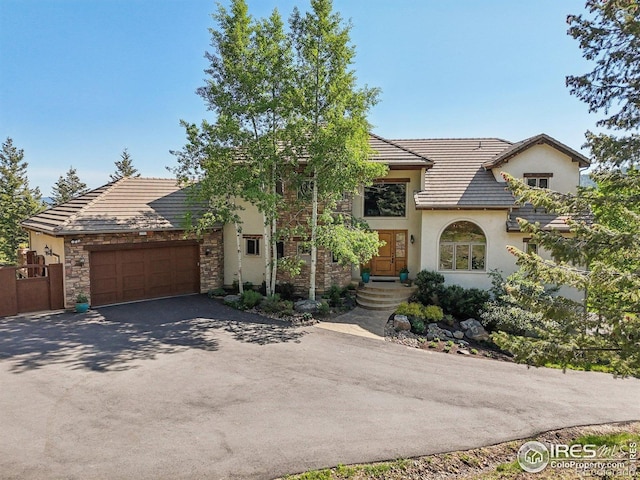 27921 Alabraska Ln, Evergreen, CO 80439 - view of front facade with asphalt driveway, an attached garage, stucco siding, and a tiled roof
