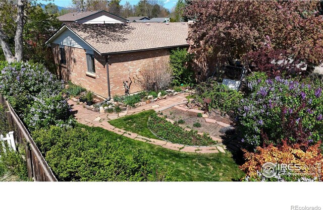 729 Jay Pl, Berthoud, CO 80513 - view of side of property featuring fence, a shingled roof, and brick siding