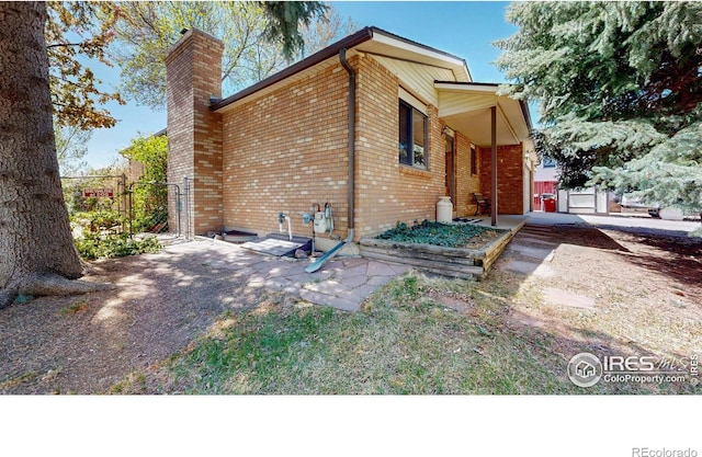 729 Jay Pl, Berthoud, CO 80513 - view of side of home featuring brick siding, fence, a chimney, and a gate