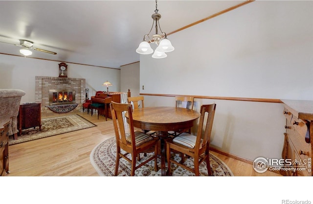 729 Jay Pl, Berthoud, CO 80513 - dining room with light wood-style floors, a brick fireplace, and ceiling fan with notable chandelier