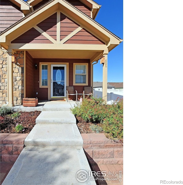 view of exterior entry featuring covered porch and stone siding