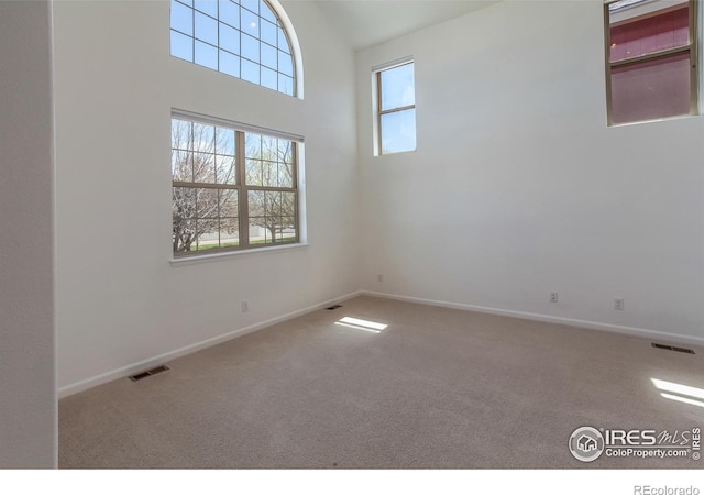 carpeted spare room with visible vents and baseboards