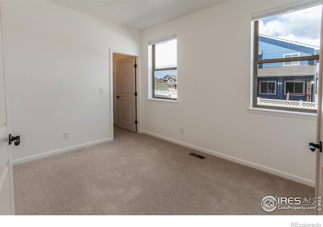 carpeted spare room with baseboards and visible vents