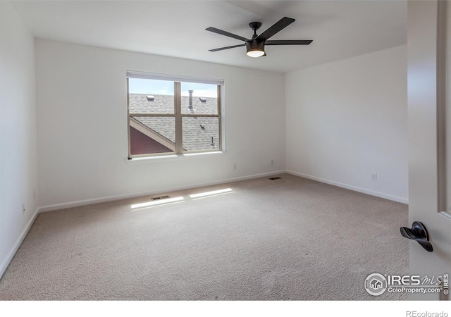 empty room featuring carpet floors, baseboards, ceiling fan, and visible vents