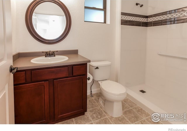 bathroom featuring vanity, tile patterned flooring, a tile shower, and toilet