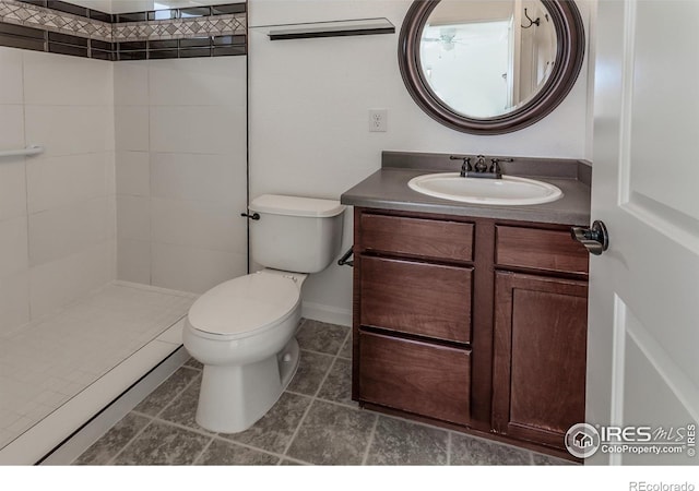 full bath with vanity, tile patterned flooring, a tile shower, and toilet