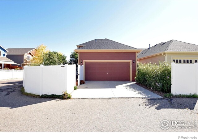 view of front facade featuring concrete driveway, an attached garage, and fence