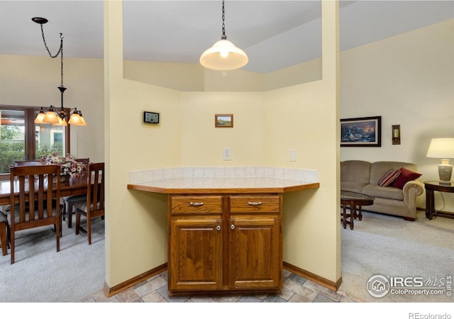 3500 Carlton Ave Unit 34, Fort Collins, CO 80525 - kitchen with light colored carpet, brown cabinetry, baseboards, and a notable chandelier