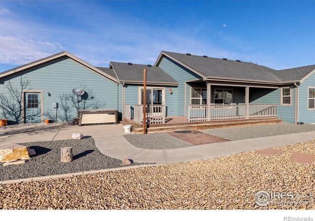 7548 County Road 100, Wellington, CO 80549 - rear view of house featuring a jacuzzi, a patio, roof with shingles, and a porch