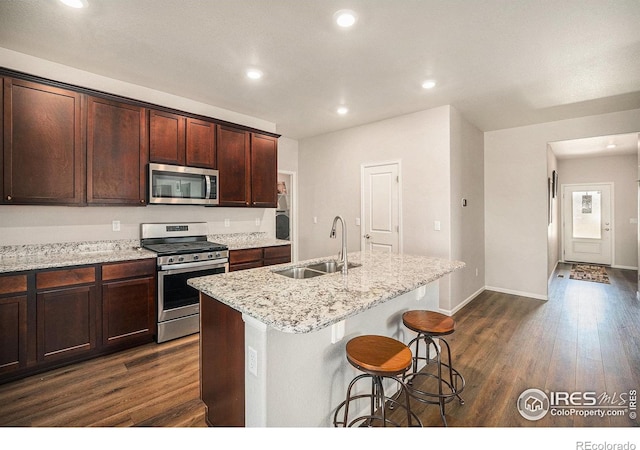 kitchen featuring a sink, appliances with stainless steel finishes, dark wood finished floors, and an island with sink