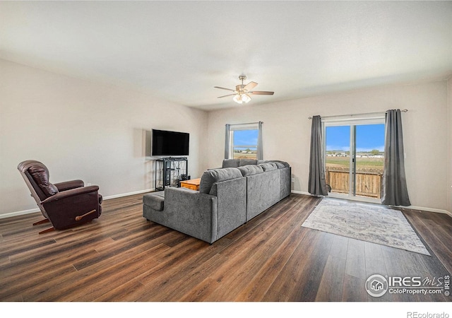 living area featuring baseboards, dark wood finished floors, and ceiling fan