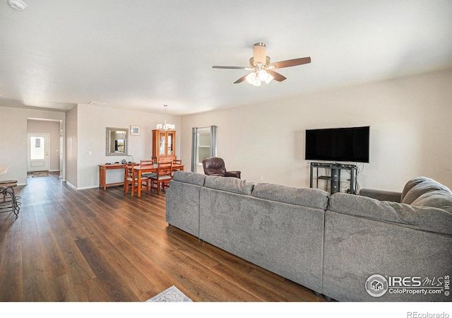 living room featuring baseboards, ceiling fan with notable chandelier, and dark wood-style flooring