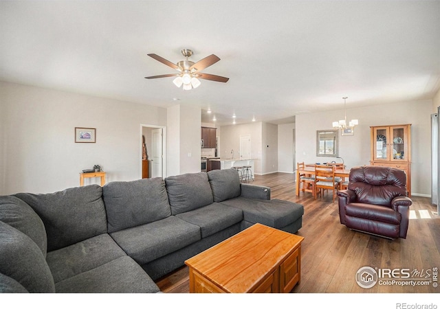 living area with baseboards, ceiling fan with notable chandelier, recessed lighting, and wood finished floors