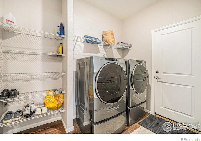 laundry area with baseboards, laundry area, wood finished floors, and washer and clothes dryer