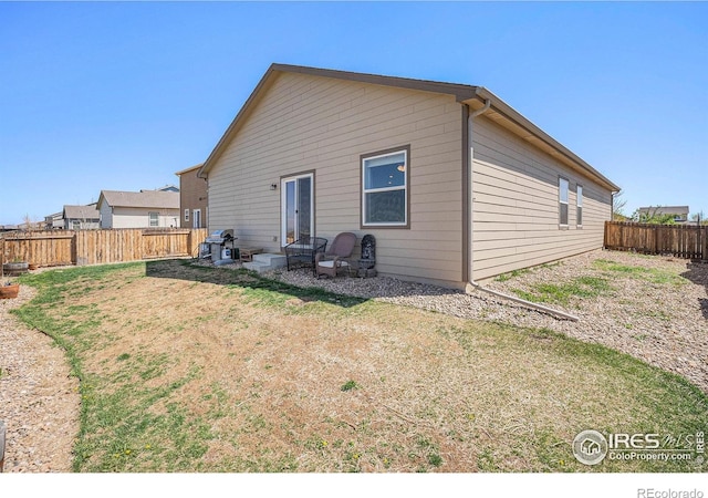 back of property featuring a fenced backyard and a yard