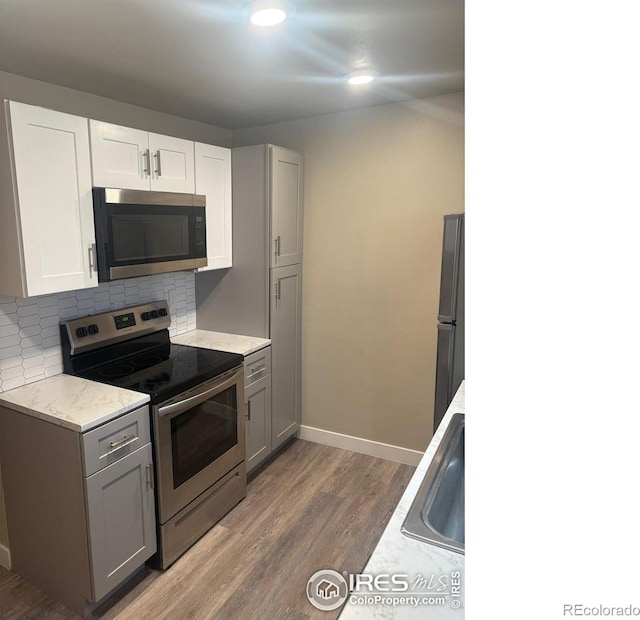 221 Chestnut St, Windsor, CO 80550 - kitchen with stainless steel appliances, light wood-style flooring, decorative backsplash, gray cabinets, and a sink