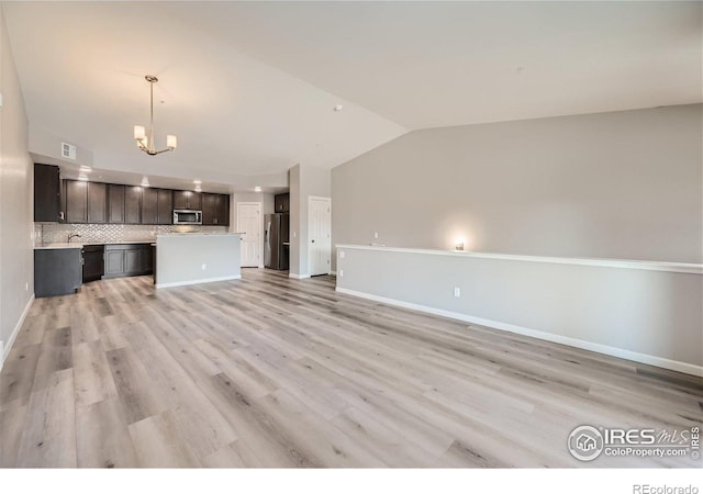 unfurnished living room featuring visible vents, lofted ceiling, baseboards, a chandelier, and light wood-style flooring