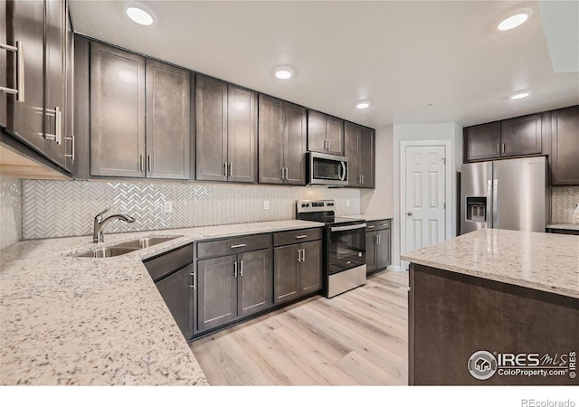 kitchen with light wood-style floors, a sink, dark brown cabinetry, and stainless steel appliances