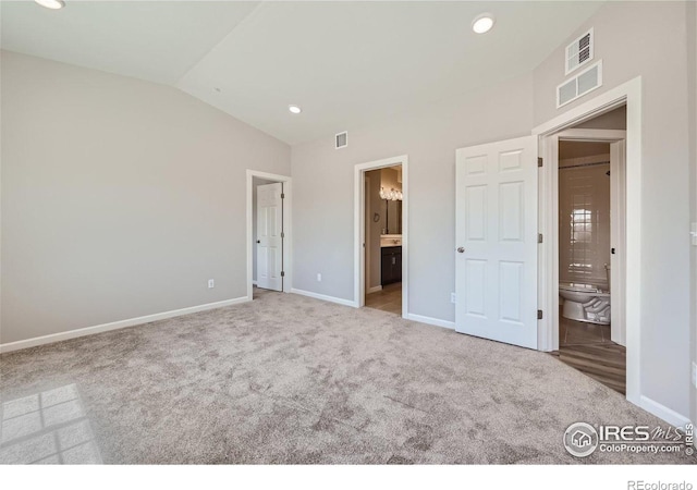 unfurnished bedroom with visible vents, carpet floors, ensuite bath, and vaulted ceiling