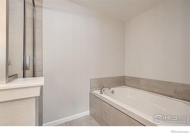 full bathroom with baseboards, tile patterned floors, and a bath