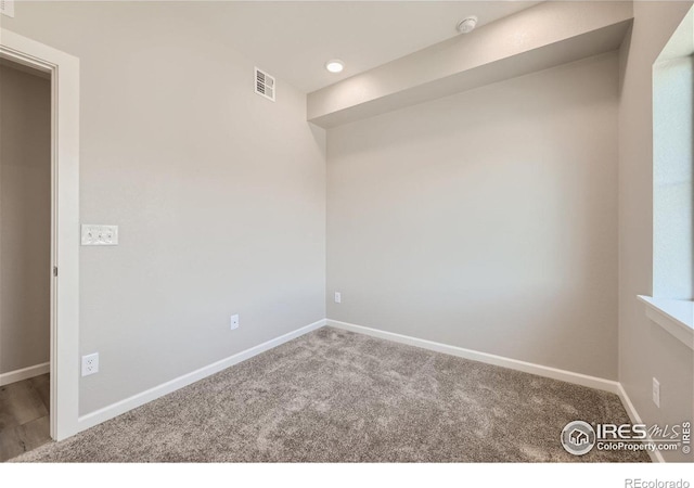 carpeted spare room featuring baseboards and visible vents