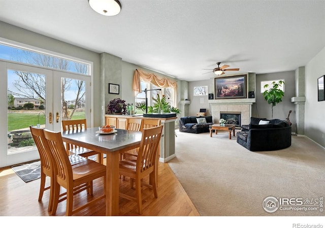665 Glenarbor Cir, Longmont, CO 80504 - dining room with french doors, a ceiling fan, a fireplace, light wood-type flooring, and baseboards