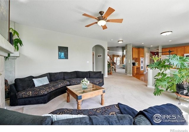 665 Glenarbor Cir, Longmont, CO 80504 - living area featuring a fireplace, arched walkways, ceiling fan, and light carpet