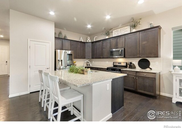 719 Wagon Bend Rd, Berthoud, CO 80513 - kitchen with appliances with stainless steel finishes, dark wood finished floors, dark brown cabinets, a sink, and light stone counters
