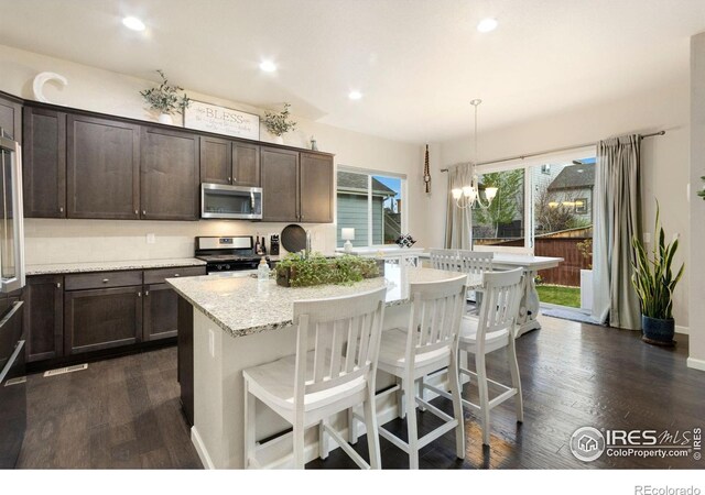 719 Wagon Bend Rd, Berthoud, CO 80513 - kitchen with appliances with stainless steel finishes, a center island with sink, dark wood-style flooring, and dark brown cabinets