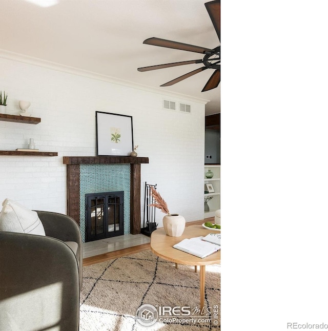 living room featuring ceiling fan, visible vents, wood finished floors, and ornamental molding