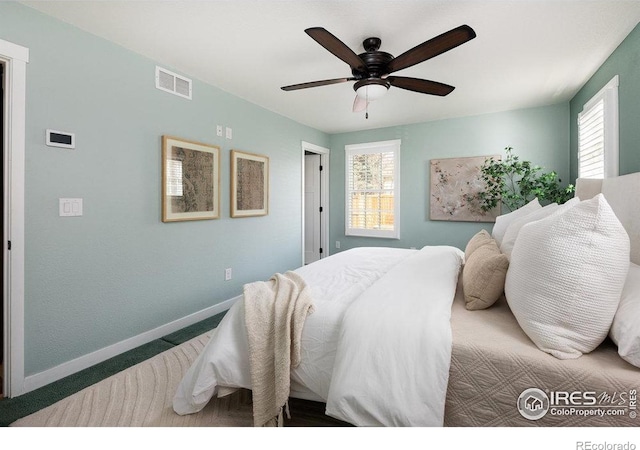 bedroom with carpet floors, baseboards, visible vents, and multiple windows