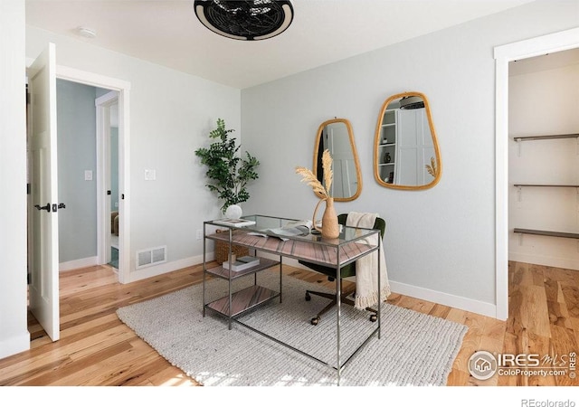 office space featuring baseboards, visible vents, and wood finished floors