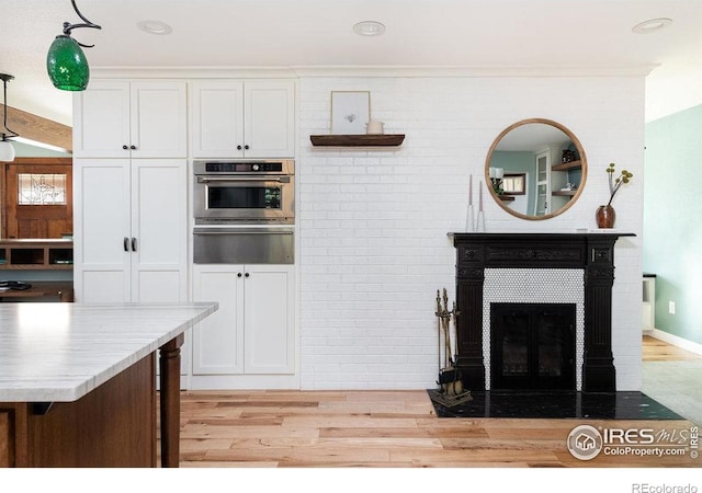kitchen with light wood-style flooring, a warming drawer, white cabinetry, and oven