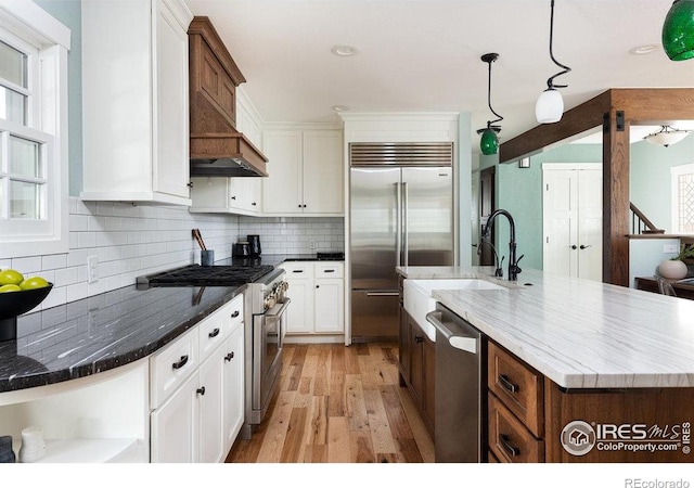 kitchen featuring open shelves, high end appliances, light wood-style floors, white cabinetry, and a sink
