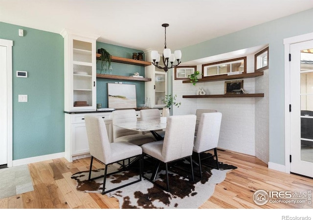dining space featuring an inviting chandelier, light wood-style flooring, and baseboards