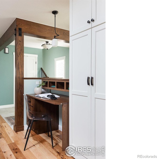 interior space with pendant lighting, white cabinetry, and light wood-type flooring
