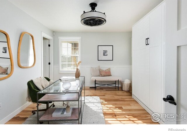 home office with a wainscoted wall and light wood-type flooring