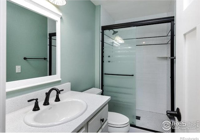 bathroom featuring vanity, toilet, and a shower stall