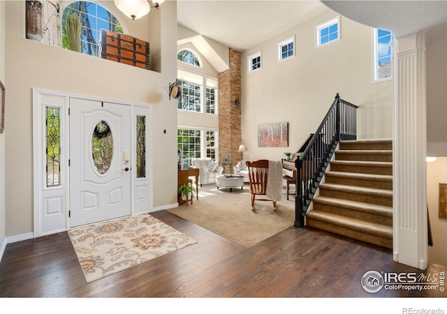 5442 Tiller Ct, Windsor, CO 80528 - foyer with decorative columns, a towering ceiling, wood finished floors, and stairway