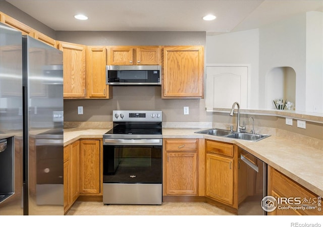 kitchen with appliances with stainless steel finishes, a sink, light countertops, and recessed lighting