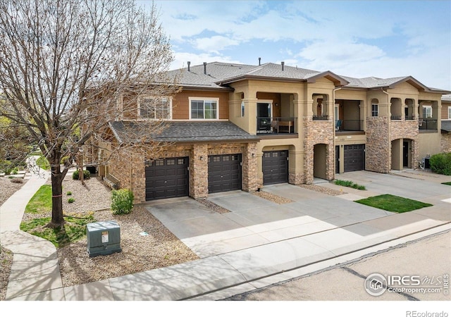 view of property featuring a balcony, a garage, driveway, stone siding, and stucco siding