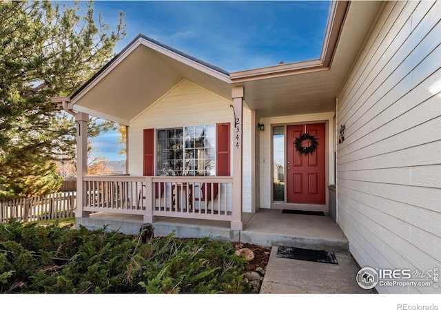 property entrance featuring a porch and fence