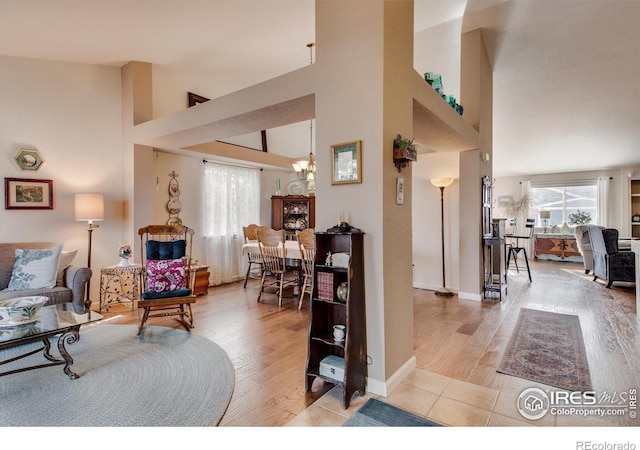 living area featuring light wood-type flooring, a towering ceiling, and a notable chandelier