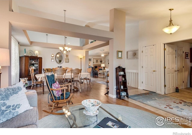 living room featuring a raised ceiling, wood finished floors, and a notable chandelier