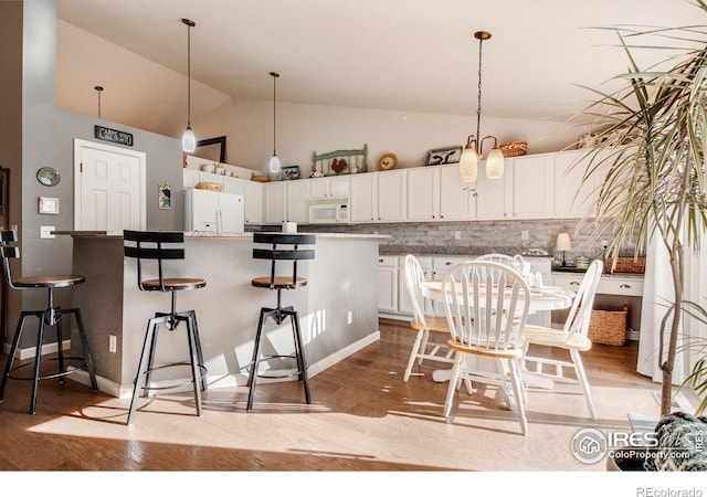 dining area featuring high vaulted ceiling and light wood finished floors