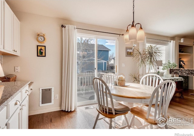 dining room featuring a healthy amount of sunlight, baseboards, light wood-style floors, and a notable chandelier