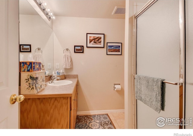 bathroom with visible vents, tile patterned flooring, vanity, baseboards, and a shower with door