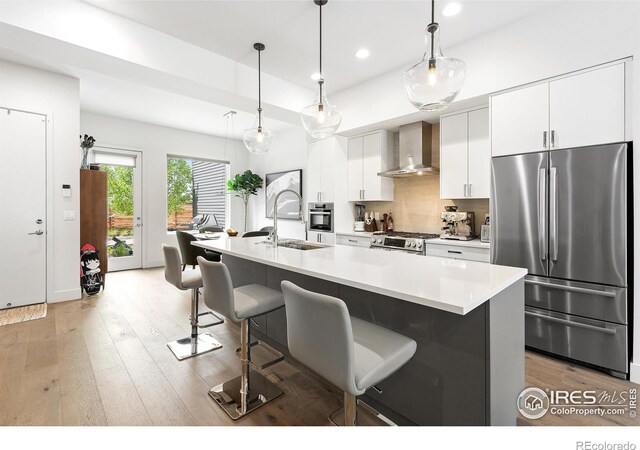 2907 32nd St, Boulder, CO 80301 - kitchen featuring stainless steel appliances, wall chimney range hood, a sink, recessed lighting, and white cabinetry